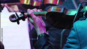 Detailed shooting, performance of a violinist on the stage. Violin in the hands of a professional musician of a symphony orchestra, playing on the stage of a classical theatre