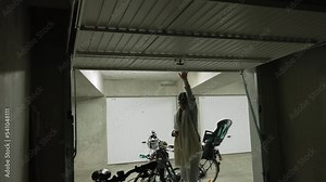 Mother opening storage room in underground parking space. Person opens metal gate interior