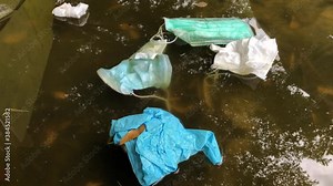 Used infectious masks and medical glove floating in dirty water,dimly light.Infectious waste,prevented virus covid-19 or germ by separating infected waste.Waste management system concept.
