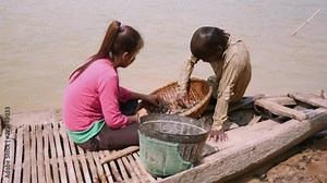 Clam diggers (husband and wife) sorting river clams out from rocks in a bamboo basket and keeping it in a basin