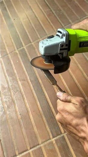 grinding metal rod using handheld power tool to smooth surface and remove rust layer slowly today