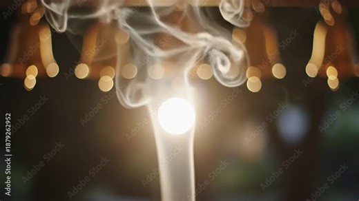Wisps of White Smoke Rise Mysteriously Around a Bright Glowing Orb With Softly Blurred Golden Bell Shapes in the Background Creating an Ethereal and Tranquil Atmosphere
