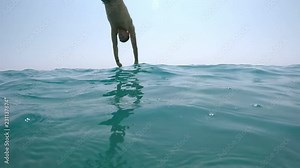 Overwater and underwater shot of a middle-aged man in shorts diving head first in crystaline sea waters on a sunny day in summer in slow motion Stock Video