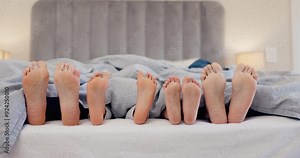 Sleeping, feet and family wake up in a bed with morning energy, movement or bond in their home together. Barefoot, love and kids with parents in a bedroom after sleep, nap or resting on vacation