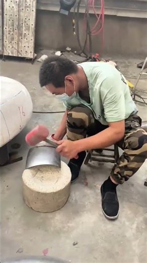 Worker shaping curved metal sheet using rubber mallet for precise industrial fabrication process