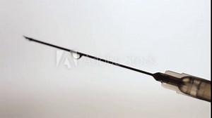 vaccination concept, syringe with clear liquid inside close up. dripping drops from the needle. soft grey background. horizontal slow motion macro HD video.