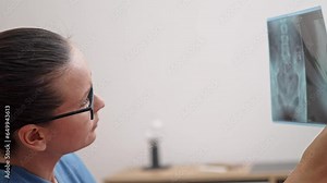 Young doctor examines X-ray image of patient closeup side view woman medic works with examination data sitting in office on blurred background work in modern clinic