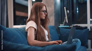 Side view: charming concentrated author write a novel keyboarding on modern laptop computer creative young caucasian woman blogging enjoying distance job working at home modern apartment freelance