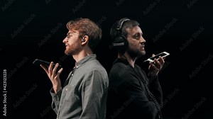 Two young men in headphones with their backs to each other talking in a voice chat