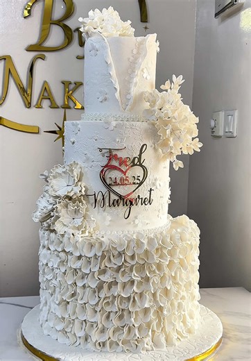 Celebrating Fred & Margaret🤍24.05.25 🤍 Three stunning tiers of pure white beauty adorned with sugar flowers and delicate ruffles. We make the most beautiful wedding cakes in Ghana. For bookings/enquiries,kindly call or whatsapp 0503694749. #LuxuryCakes #ElegantCakes #cakesbynak #whiteweddingcake #weddingcakesinghana #cakevendorsinghana #3tierweddingcakes #cakesontiktok