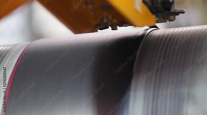 Detailed production process of car tires, close-up. Rubber tape is reeled up on a drum in the machine. Closeup smooth processed rubber bands pass between roller mechanism in powerful tire company.