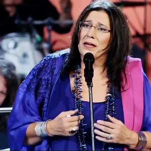 One of Mikis's most iconic songs, sung by his most iconic singer. Maria & 'Song of Songs' (Mauthausen Cantata). Herodion, 17.9.2013. '' 'Ασμα Ασμάτων'' Τι ωραία που είν' η αγάπη μου με το καθημερνό της φόρεμα κι ένα χτενάκι στα μαλλιά. Κανείς δεν ήξερε πως είναι τόσο ωραία. Κοπέλες του Άουσβιτς, του Νταχάου κοπέλες, μην είδατε την αγάπη μου; Την είδαμε σε μακρινό ταξίδι, δεν είχε πιά το φόρεμά της ούτε χτενάκι στα μαλλιά. Τι ωραία που είν' η αγάπη μου, η χαϊδεμένη από τη μάνα της και τ' αδελφού 