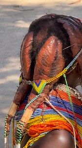 The hair of Mumuila women from the plains of southern Angola is one of the most distinctive features of their cultural identity.They use a traditional mixture of red clay, ghee, ash, and herbs to coat their hair, forming thick braids or locks that are styled in different ways depending on age and marital status.Young girls often have their hair completely covered in clay, while married adult women adorn it with beads and leather strips. This hairstyle is not only aesthetic but also symbolic, ref