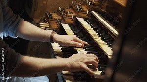 Expert organist plays a large church organ keyboard. Hands move quickly improvising sacred music. Musician presses keys and adjusts the sound with stops and rods and also uses foot pedals. Stock Video