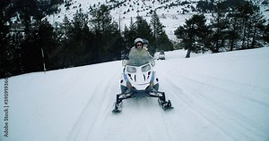 Snowmobiles on snowy road in the forest. Group of friends doing perfect leisure mountain activity, with a woman driving a snowmobile 4K