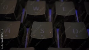 Close-up macro footage of a glowing RGB keyboard. The shot captures the intricate details of the backlit keys, showcasing a vivid array of colors and dynamic lighting effects