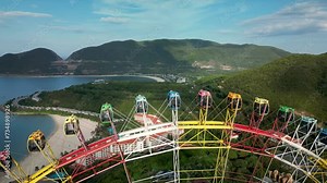 Colorful Ferris wheel spinning slowly in amusement park with sky in the background. Ride on carousel represents entertainment and fun. Endless loop. Sunset in background.Colorful Ferris wheel spinning