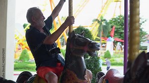 Happy Senior couple enjoy life travel on a carousel in amusement park together. activity ageing . elderly retirement lifestyle . fun fair