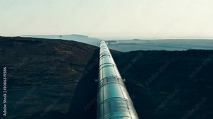 Long Straight Pipeline Extending Into the Horizon Across a Rugged Landscape with Clear Sky in the Background and Distant Mountains on the Edge of the View