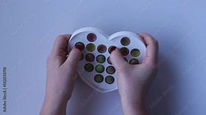 Women hands crumple and play with large heart Pop It close-up top view. Board game for the development of motor skills. Trendy toy Big Pop It fidget. Popit gamer. Antistress toy