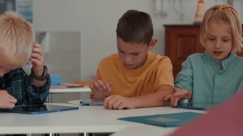 clip-3975092065-group-schoolkids-using-tablets-laptops-class