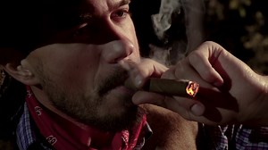 Cowboy with a cigar in the forest at night. Life in the wild west of America. Close-up 4K