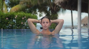 Beautiful Young Girl Popping Out of Water in Pool Looking At Camera