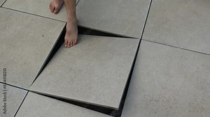 Floor tile opening and collapsing, indicating dangerous construction structures.