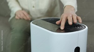 Woman hand on air purifier. A woman puts her hand on the air smart purifier to switch it on in the living room.