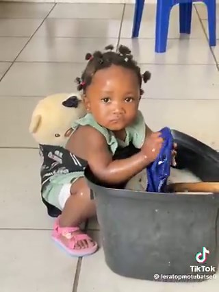 She is in the Autonomy vs. Shame and Doubt stage of Erik Erikson, where children begin to develop independence by copying what they observe. She understands that she needs to bathe, but she hasn’t yet learned the correct way to do it.At this stage, children either build confidence in their abilities or begin to doubt themselves, depending on the support they receive.