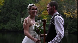 bride and groom posing at end of dock on lake having fun 4k