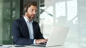 A corporate operator who works in customer support speaks on a video call using a laptop computer. Call center agent in wireless headset helping clients with complaints in office. Online consultation