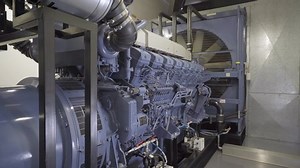 Tracking shot of giant standby diesel backup generator at data center.