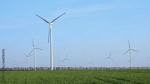 Aerial fly around wind turbines across spring agricultural field. Clean and Renewable Wind Power Farm in Motion. Green energy, sustainable alternative electricity, no pollution environment.