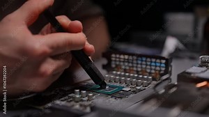 Technician applying thermal paste to GPU chip for improved circuit board cooling efficiency. Precise application new thermal pad onto graphics processing unit in workshop. Shooting in slow motion.