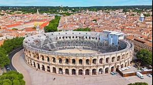 Aerial view of Imposing Roman amphitheatre hosting historic reconstructions in Nimes, France. View from above Amphitheatre of Nîmes and Museum Romanité in France.
