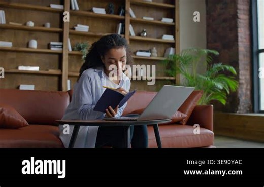 Young female student writing notes in a notebook while attending an online educational class on a laptop, showing focus, learning, and study routine Stock Video Footage - Alamy