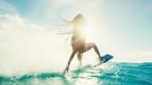 Beautiful young woman kiteboarding at sunset in slow motion, active...
