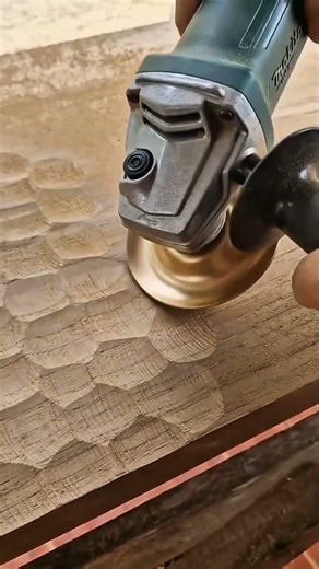 Wood carving using a power angle grinder with a circular gold carving disc on a thick wooden board