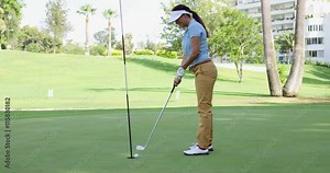 Woman golfer lining up for a putt on the green viewed from the point of view of the flag in the hole