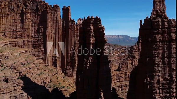 Fisher Towers showcasing dramatic red Cutler sandstone formations under a clear blue sky. Aerial Dolly Left