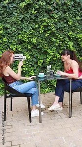 Two friends recording themselves with an old video camera while having coffee