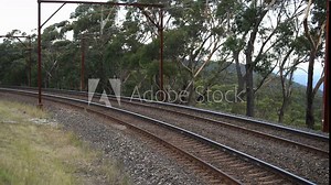 An Intercity communter train passes by on tracks next to the national park, with views of the Megalong Valley, Blue Mountains.