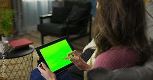 Woman could be an avid reader, engrossed in an e-book or digital magazine on the laptop. The green mockup screen suggests her access to a vast digital library.