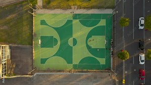 Local basketball team practicing shooting hoops on outdoor basketball court.