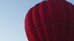 Red hot air balloon floating gently against a blue sky - Free Stock Video