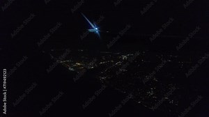 Airplane window view night approach flying over seaside town lights generic plane dark