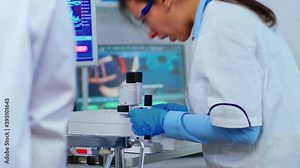 Biochemical research scientist team working with microscope for vaccine development in pharmaceutical labolatory. Stuff examining virus evolution using high tech researching diagnosis against covid19