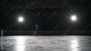 The girl skater performs a jump with the rotation of a triple toe loop in a counter light on an ice cat. Slow-motion jump in figure skating