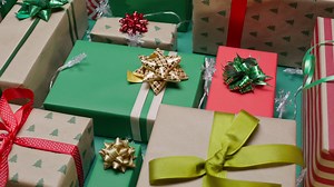 A collection of wrapped gifts in various colors of wrapping paper, including green, red, and beige with Christmas tree patterns. - Free Stock Video
